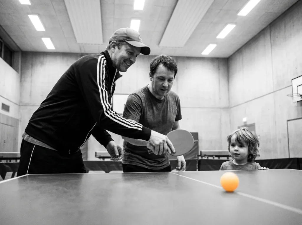 Trainer zeigt einem Anfänger die Schlägerhaltung, ein Kind schaut zu